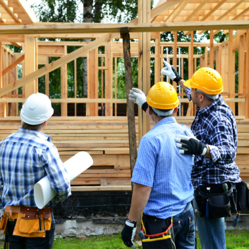 three men discussing work over a house bieng built